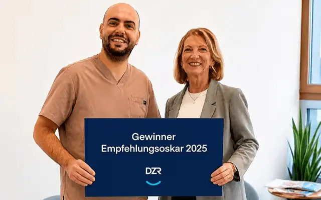 Zahnarzt und DZR-Mitarbeiterin halten gemeinsam Schild mit Aufschrift „Gewinner Empfehlungsoskar 2025"